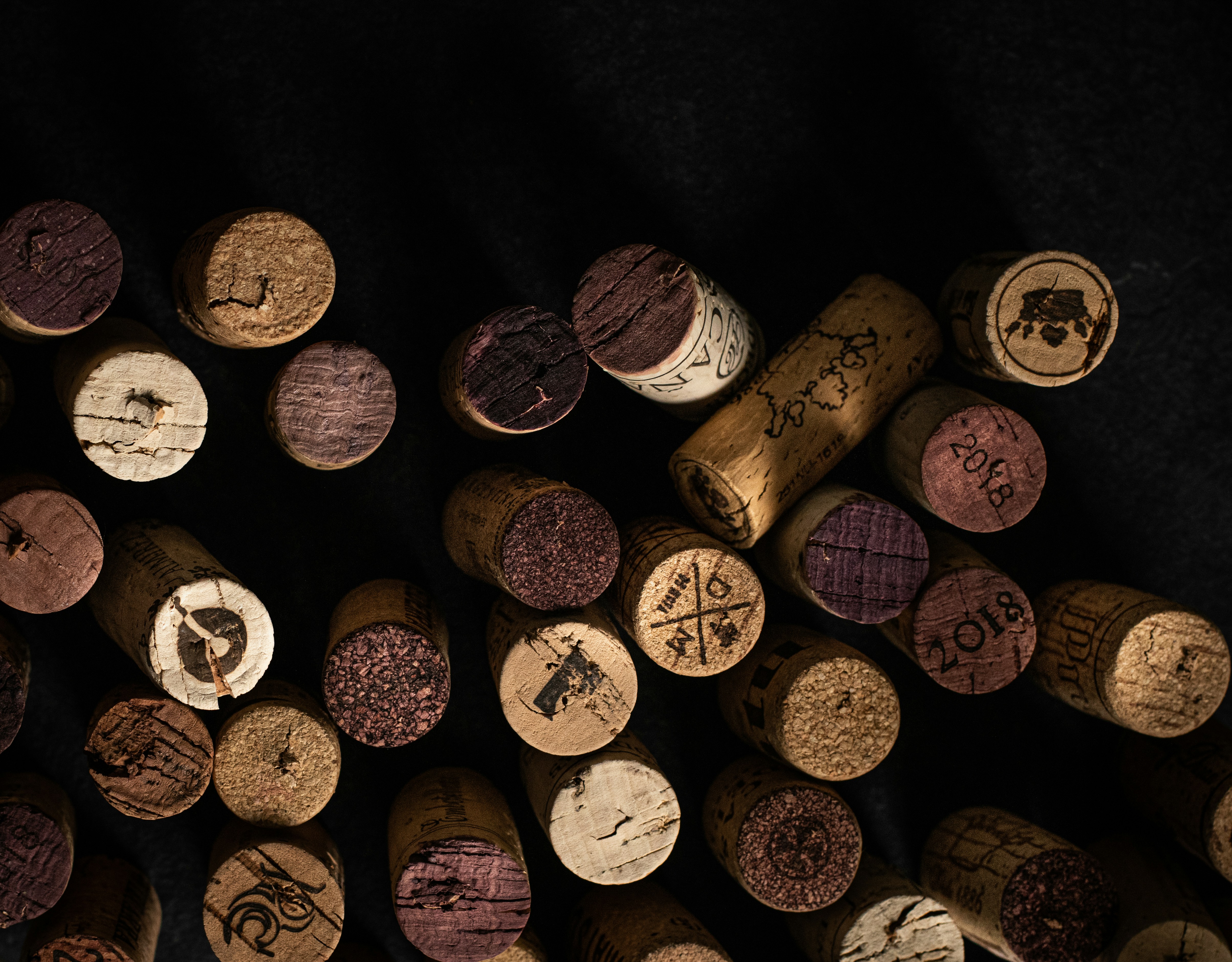 A collection of assorted wine corks on a dark background.