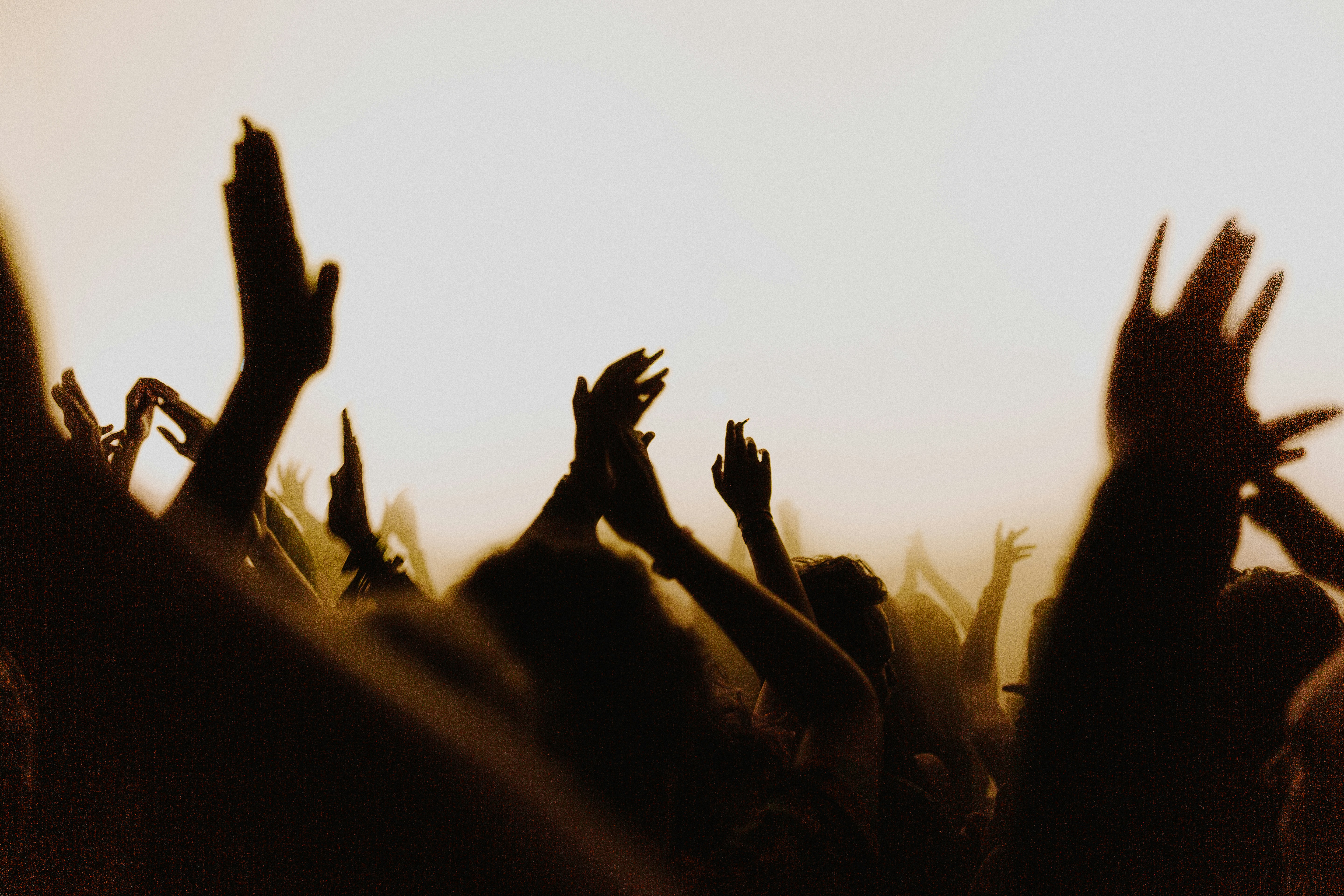 A crowd of arms reaching upward to clap, presumably at a concert.