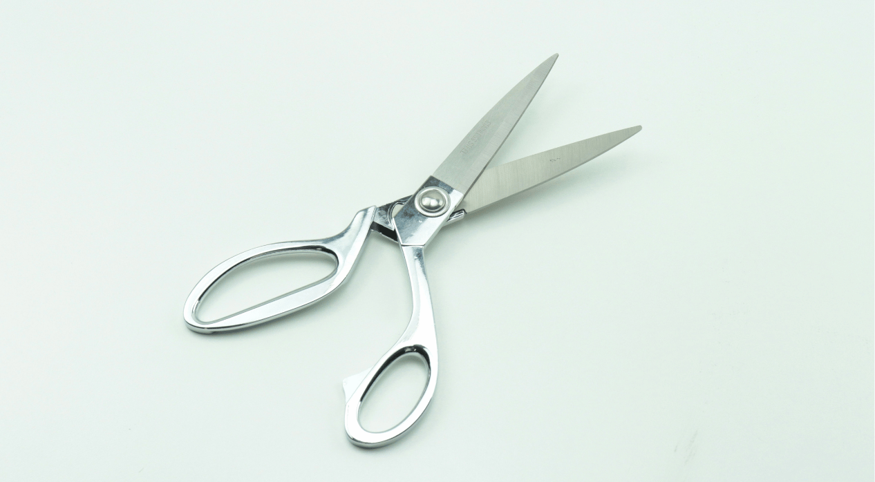 A pair of metallic silver scissors with open blades on a white background.
