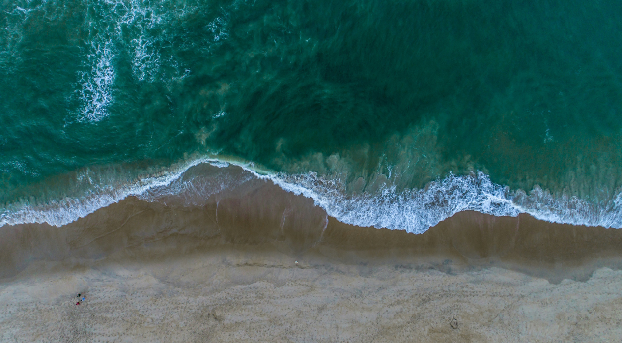 Aerial view of ocean waves meeting a sandy beach.