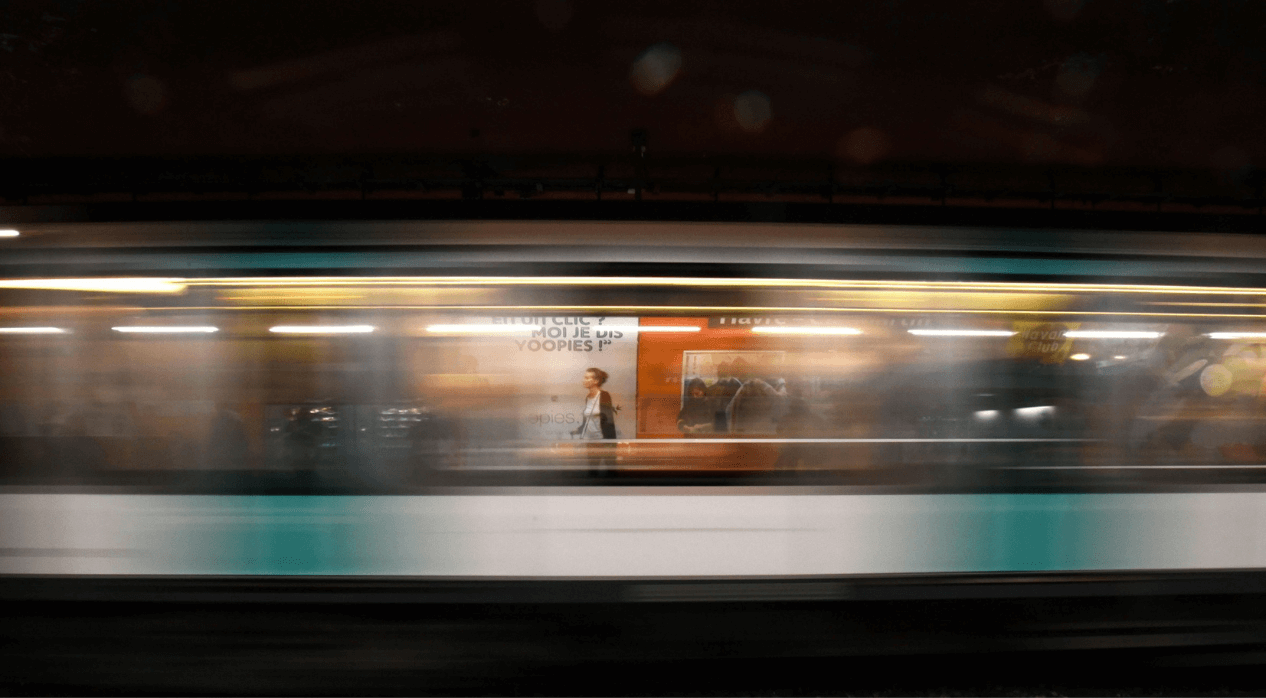 A speeding train in motion at an underground station, with motion blur obscuring details.