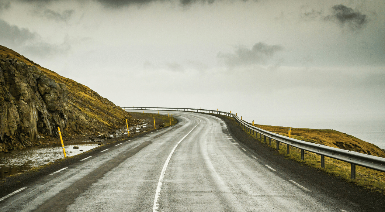 Bend in the road on the side of a hill with cloudy sky