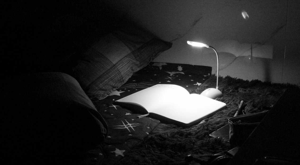 Lamp lighting an empty page on top of bed.